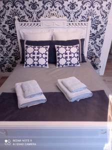 ein weißes Bett mit Kissen und Handtüchern darauf in der Unterkunft La Gravière 