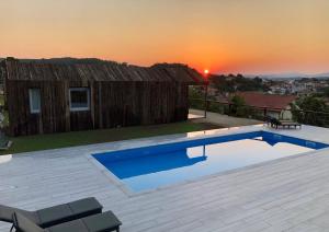 a swimming pool with a sunset in the background at Cabañas Rias Baixas in A Pobra do Caramiñal