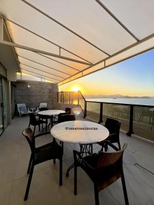 a balcony with tables and chairs and a view of the ocean at Cobertura Quebec Beira-Mar in Balneário Camboriú