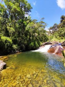 uma piscina de água em frente a uma cascata em Chalé do Coiote em Maromba em Visconde de Mauá