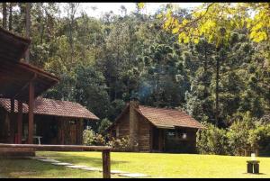 dois pequenos edifícios de madeira num campo com árvores em Chalé do Coiote em Maromba em Visconde de Mauá