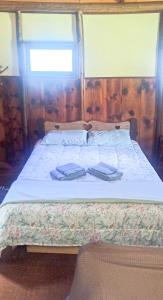 um quarto com uma cama com duas toalhas em Chalé do Coiote em Maromba em Visconde de Mauá