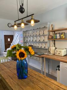 a blue vase with sunflowers on a table in a kitchen at Aurora Tor in Glastonbury