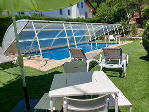 a table and chairs with an umbrella next to a pool at Casa familiar con piscina in Pallejá