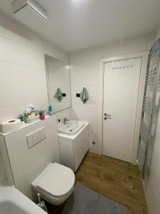 La salle de bains blanche est pourvue de toilettes et d'un lavabo. dans l'établissement Manhattan apartman A blok, à Novi Beograd