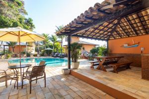 un patio con mesa, sillas y piscina en Casa em Búzios com vista mar e piscina | EDF 12, en Búzios