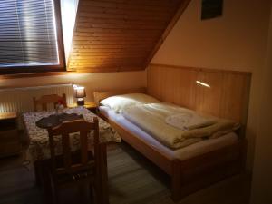 a small bedroom with a bed and a table at Pod palmou Gerlachov in Svätý Jur