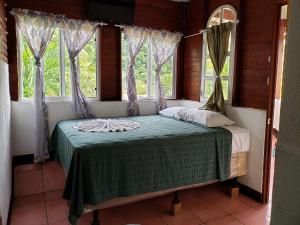 a bed in a room with two windows at Hotel y Restaurante La Cabaña el Viajero in Castillo de San Felipe