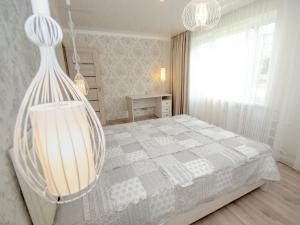 a bedroom with a bed and a chandelier at Jūras 4 Apartament in Ventspils