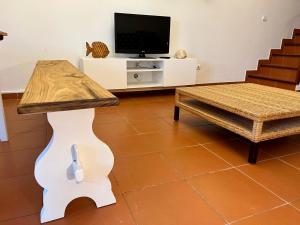 a living room with a table and a tv at Casa das Dunas in Almograve