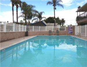 a large blue swimming pool with palm trees in the background at Raincross Hotel Riverside in Riverside