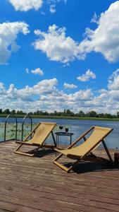 two chairs sitting on a dock next to the water at Дом в лесу на берегу Днепра для отдыха, аппартоменты in Budishche