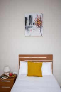 łóżko z żółtą poduszką i zdjęciem na ścianie w obiekcie PUESTA DE SOL RENTALS 2AJ w mieście Playa de San Juan