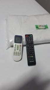 a remote control and a calculator sitting on a bed at Hotel ROF in Telêmaco Borba
