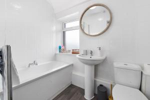 uma casa de banho com uma banheira, um lavatório e um espelho. em Village Cwtch Whitchurch 2 Bedroom Apartment em Cardiff