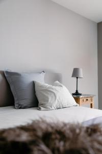 - un lit avec des oreillers blancs et une table avec une lampe dans l'établissement NeNe, à Dilbeek
