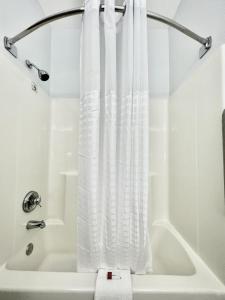a white shower curtain in a bathroom with a tub at AmericInn by Wyndham Quincy in Quincy