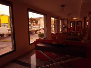 uma sala de estar com um sofá vermelho e janelas em HOTEL SANTA CRUZ em Río Gallegos