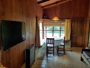 a dining room with a table and a television on a wall at Hermosa Cabaña a metros del Lago in San Carlos de Bariloche