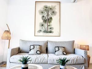 a living room with a couch with palm trees at Kalina, beautiful duplex 100m from Orient Bay beach with swimming pool in Orient Bay