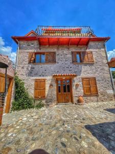 a stone house with wooden doors and a balcony at Keyifli Bir Taş Ev SAÇAKLIHANE Çanakkale Tavaklı in Ezine