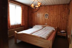 1 dormitorio con 1 cama en una pared de madera en Hotel Guidon Apartments en Bivio
