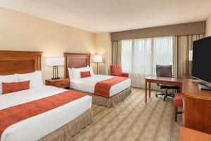 a hotel room with two beds and a desk and a television at The Inn at Virginia Tech - On Campus in Blacksburg