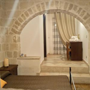 a bedroom with an archway with a bed and a table at Agriturismo Al Passaggio di Pirro in Miglionico