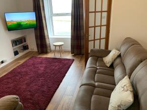 a living room with a couch and a flat screen tv at Traditional Caithness Stone house in Wick