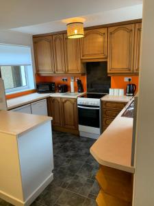 a kitchen with wooden cabinets and a white stove top oven at Traditional Caithness Stone house in Wick