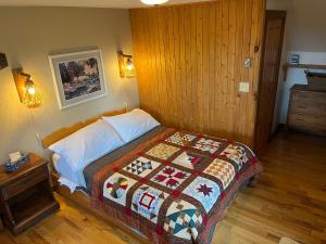 a bedroom with a bed with a quilt on it at L'Aubergine in Saint Hilarion