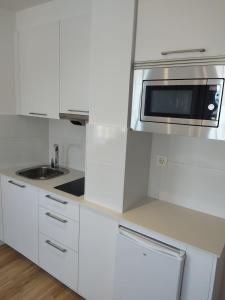 Una cocina blanca con microondas y fregadero. en P2 O Grove Centro con vistas al mar y parking, en O Grove