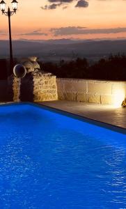 a blue swimming pool with a sunset in the background at Casale Ciricó tra Catania e Siracusa in Carlentini