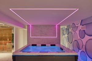 - un bain à remous dans une pièce dotée d'un mur violet dans l'établissement Riva Palace Hotel, à Grado