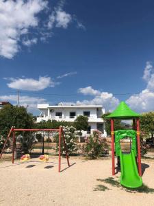 a playground with a green slide and a swing at Villa Soni Oruci in Ksamil