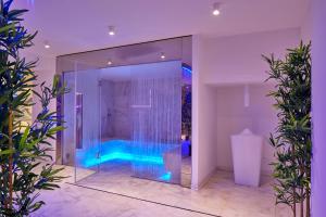 uma casa de banho com uma cabina de duche em vidro com luzes azuis em Riva Palace Hotel em Grado