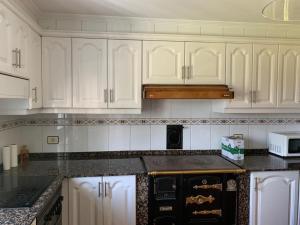 a kitchen with white cabinets and a stove top oven at Casa ferreiro in Ribadeo +11 photos