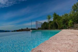 - une piscine d'eau bleue avec des palmiers dans l'établissement AntiquaeLunae Casali, à Fosdinovo