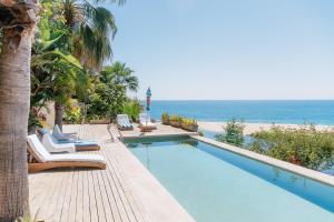 a swimming pool with chairs and the beach at Villas La Mar - Adults 15 plus in Todos Santos