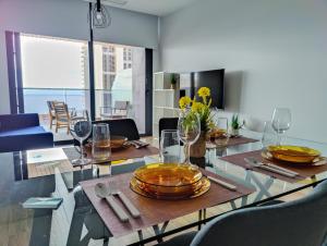 a dining room with a table with plates and wine glasses at SUNSET WAVES apARTs by RB in Benidorm