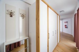 - un couloir avec des armoires blanches et du parquet dans l'établissement Pink Sahara near City Center, à Oradea