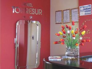 a vase of flowers on a table next to a refrigerator at Hotel Torresur Tacna in Tacna