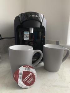two coffee cups on a counter next to a coffee maker at Crowthorne House, beautiful 3 bedroom Home for upto 8 Guests, with sofa bed Cul-de-sac with Private Driveway in Nottingham