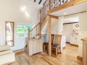 a staircase in a living room with a table and a chair at Norbank Cottage in Bressingham