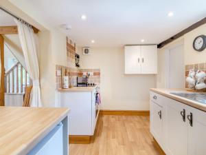 een keuken met witte kasten en een aanrechtblad bij Norbank Cottage in Bressingham +13 foto's