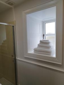 a stack of towels in a bathroom with a window at Biddy Ban’s in Carnmalin