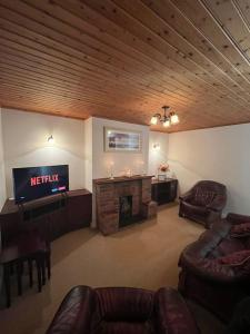 uma sala de estar com uma televisão, um sofá e uma lareira em Mc's View em Tullyrossmearan