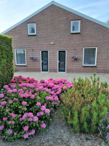 un edificio de ladrillo con flores rosas delante de él en Hemmer Hoeve, en Hem