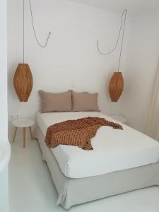 Dormitorio blanco con cama y mesa en Helen Studios en Naxos