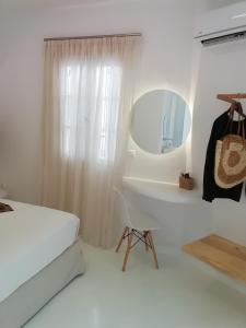 Habitación blanca con cama y espejo en Helen Studios en Naxos